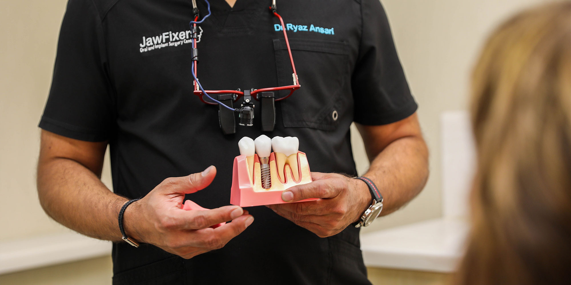 Dr. Ansari Ryaz holding a model of implant