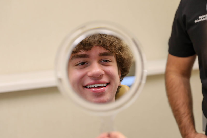patient smiling into a mirror looking at their teeth