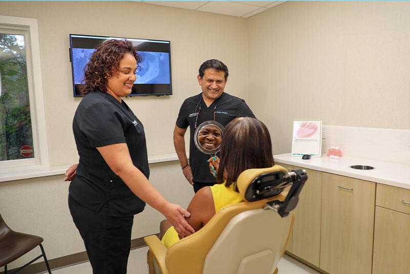 Dr. Ansari Ryaz. givving mirror to patient to see their teeth after dental procedure