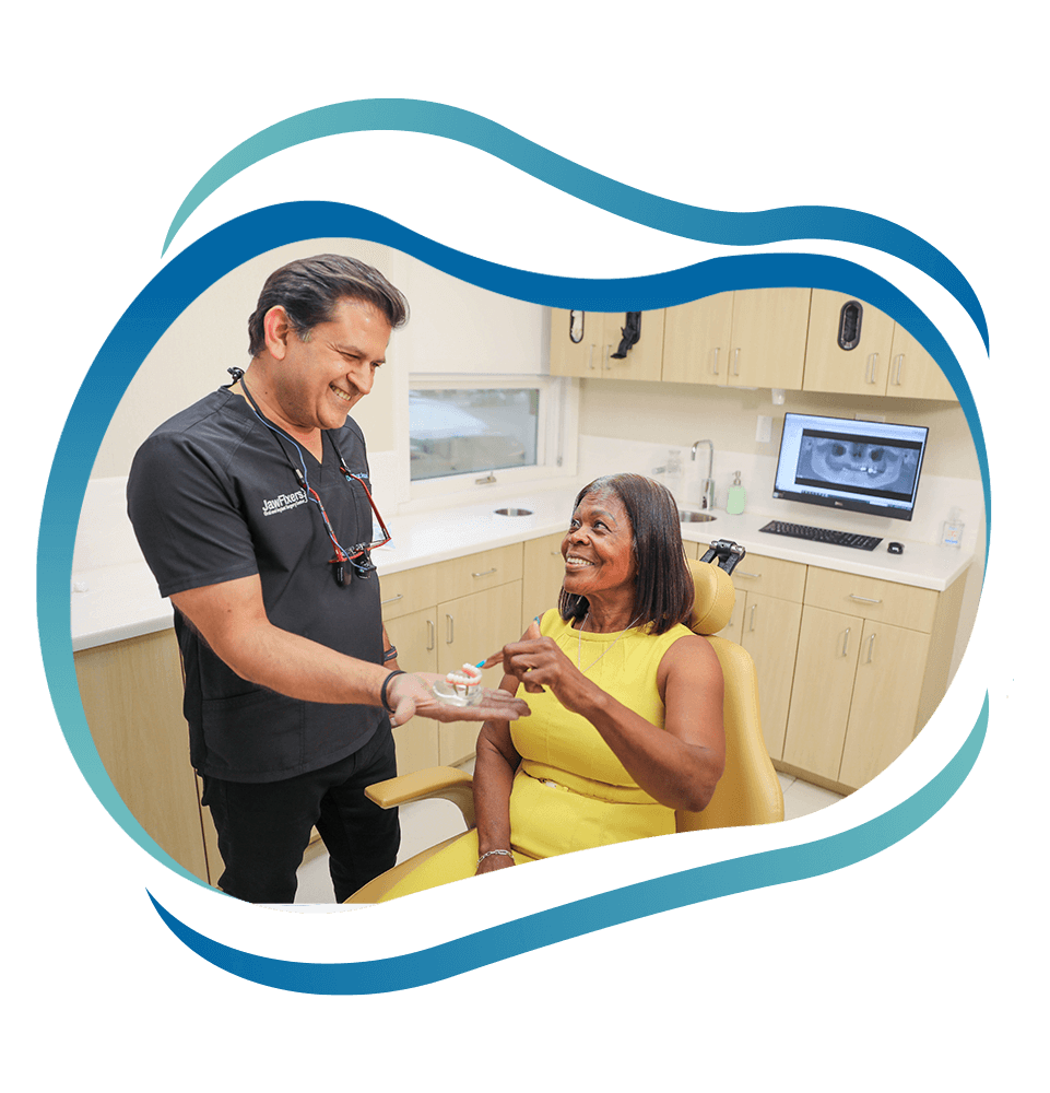 Dr. Ansari Ryaz handing a model of dental implants to patient