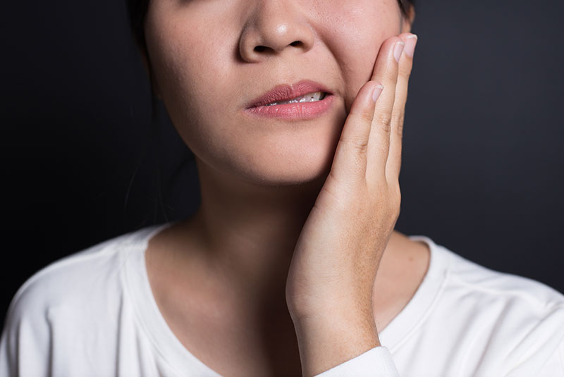 woman holding mouth in pain